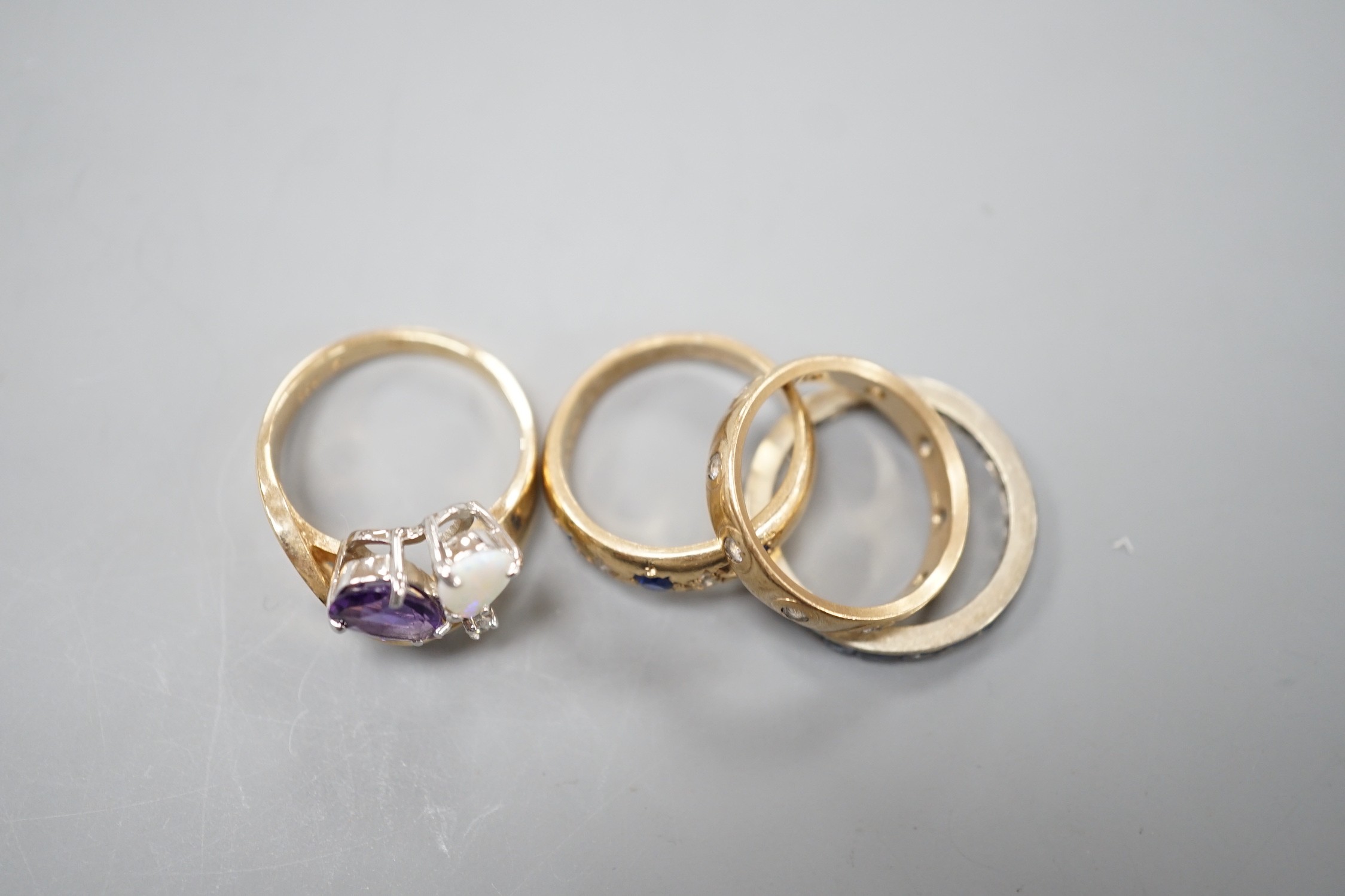 A 10k yellow metal, amethyst, white opal and diamond set dress ring, size N, gross weight 4.6 grams, two 9ct and gem set rings and a white metal and sapphire? set full eternity ring, gross weight 8.2 grams.